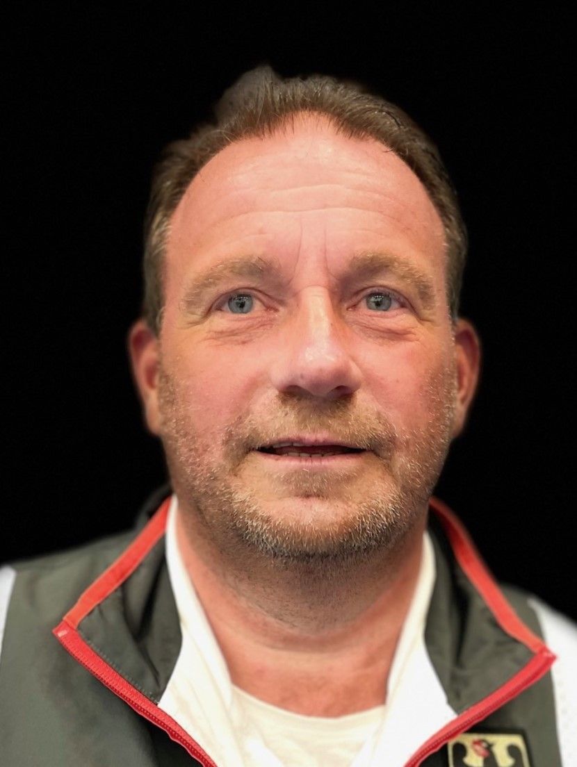 Ein Mann mit Bart und weißem Hemd schaut in die Kamera.