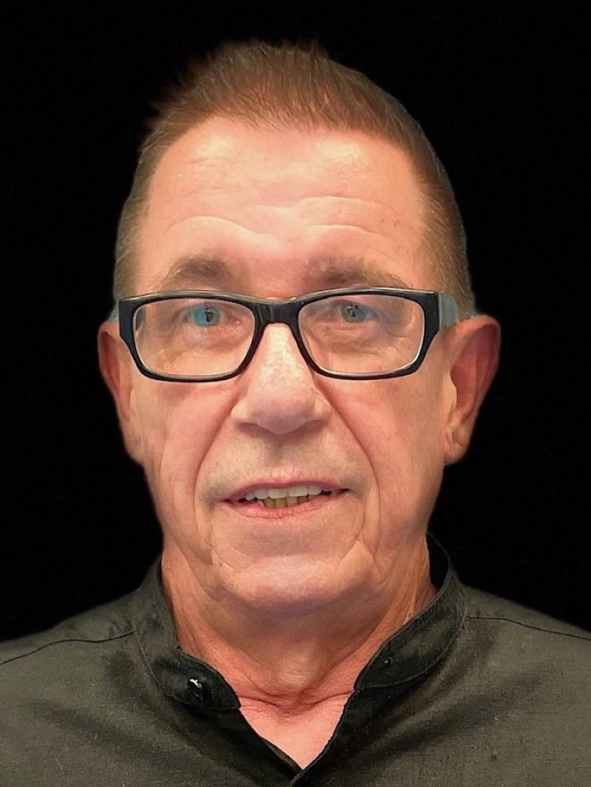 Ein Mann mit Brille und schwarzem Hemd lächelt in die Kamera.