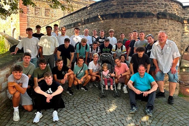 Eine Gruppe junger Männer posiert vor einer Steinmauer für ein Foto.