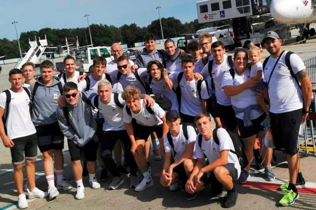 Eine Gruppe von Menschen posiert vor einem Flugzeug für ein Foto.
