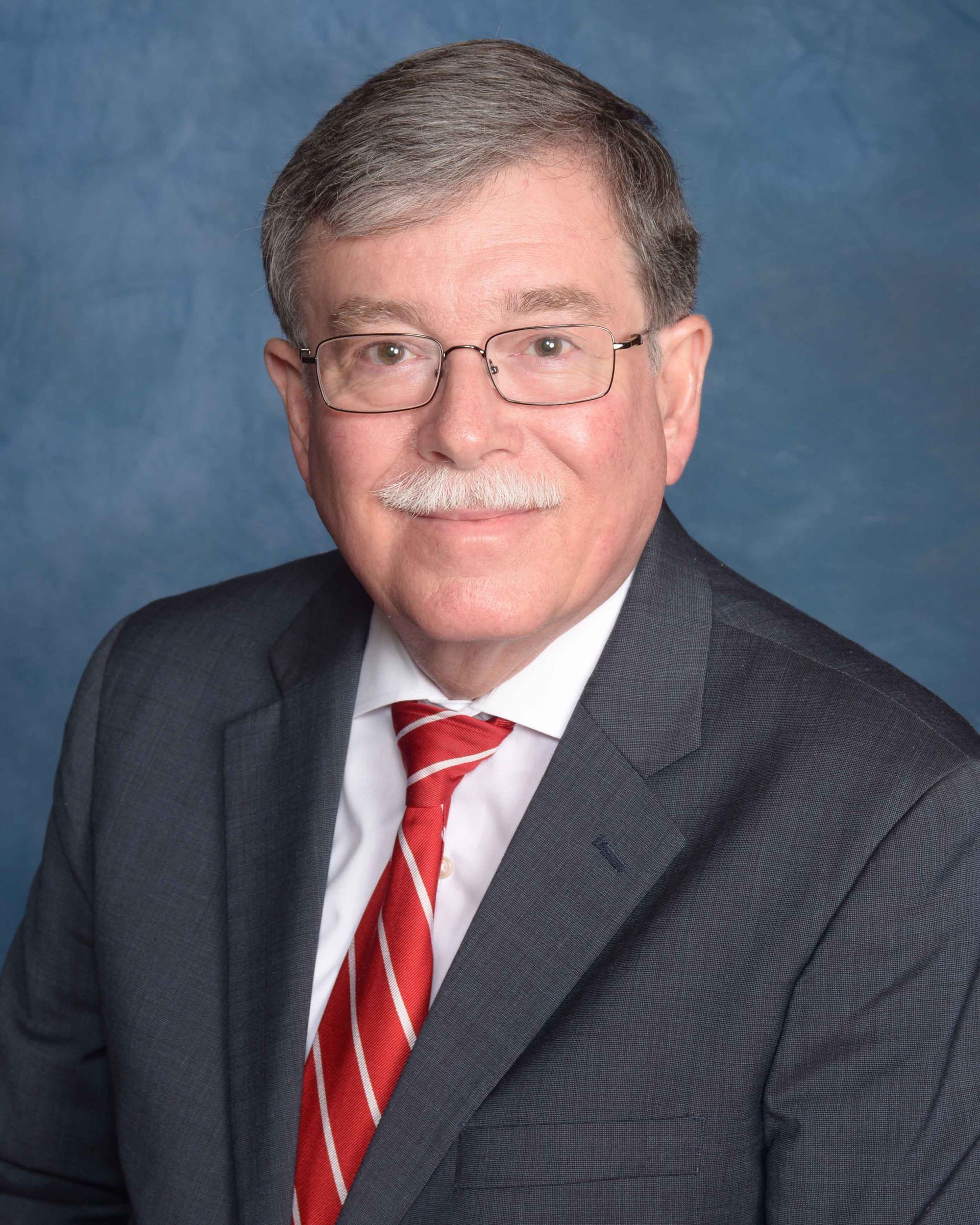 A man in a suit and tie with glasses and a mustache