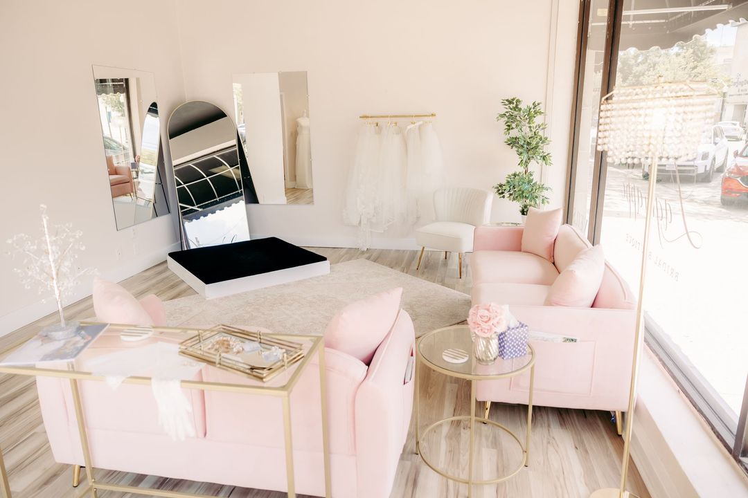 A living room with a pink couch , chair , table and mirror.