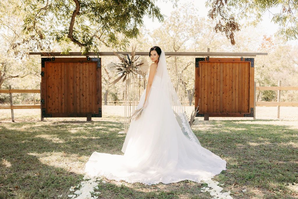 A bride in a white dress is holding a bouquet of white roses.