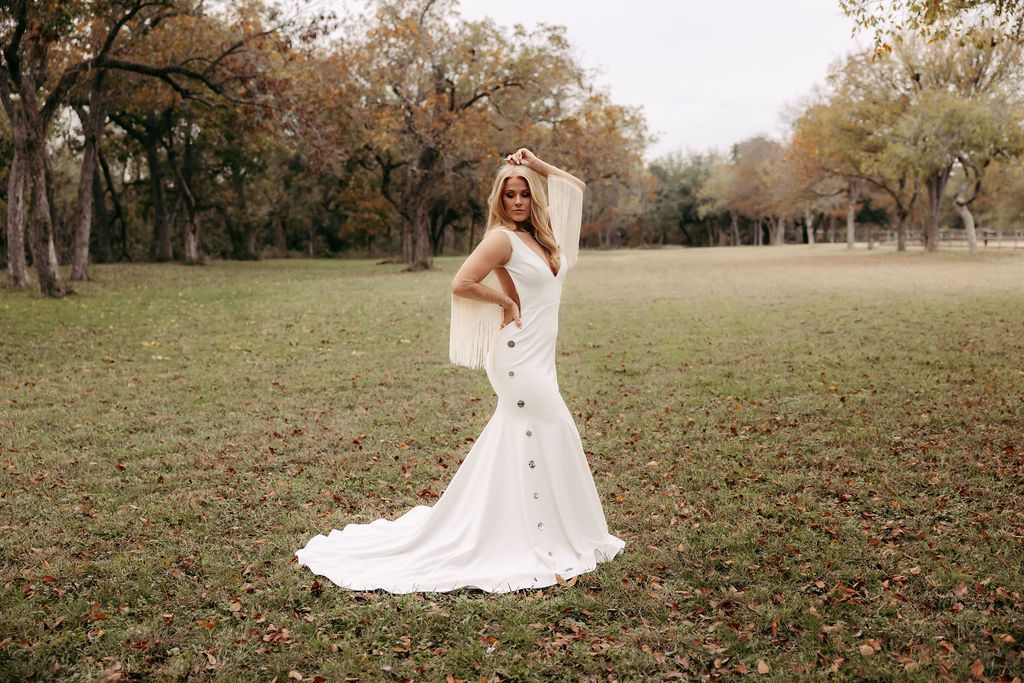 A bride in a white dress is holding a bouquet of white roses.