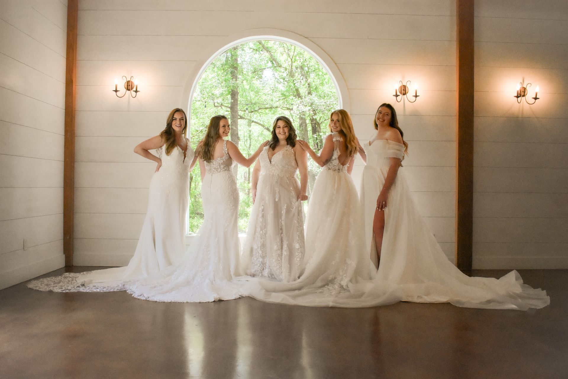 A group of women in wedding dresses are standing next to each other in a room.