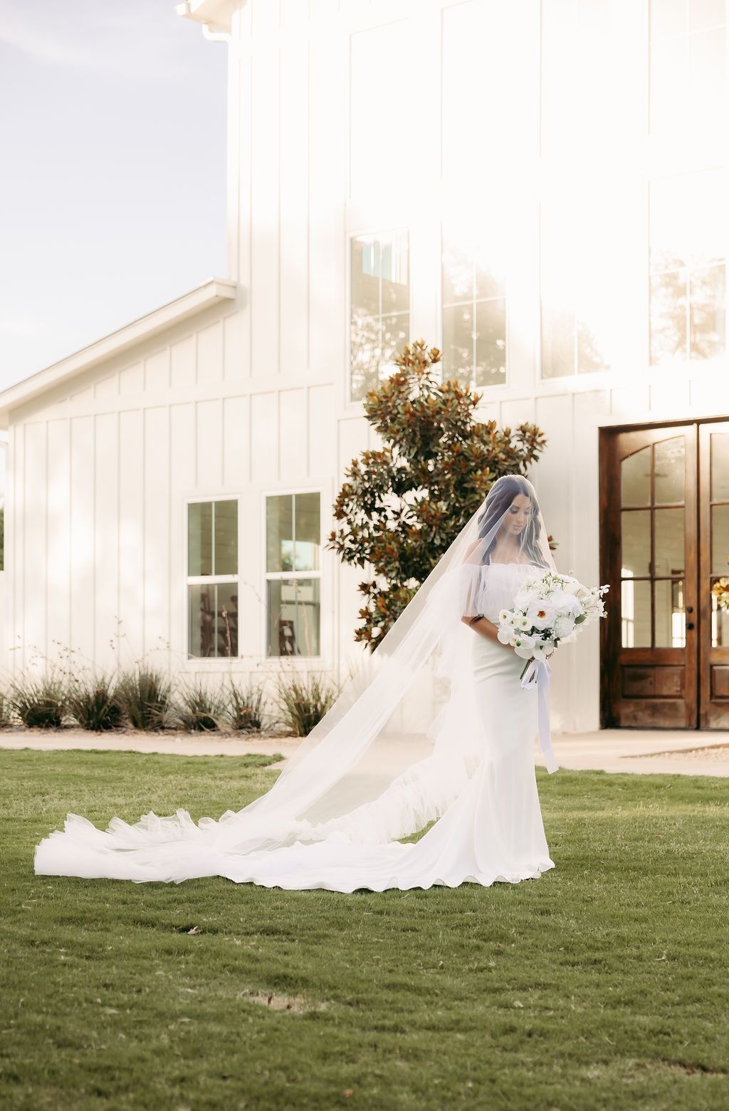 The bride is wearing a long veil and holding a bouquet of flowers.