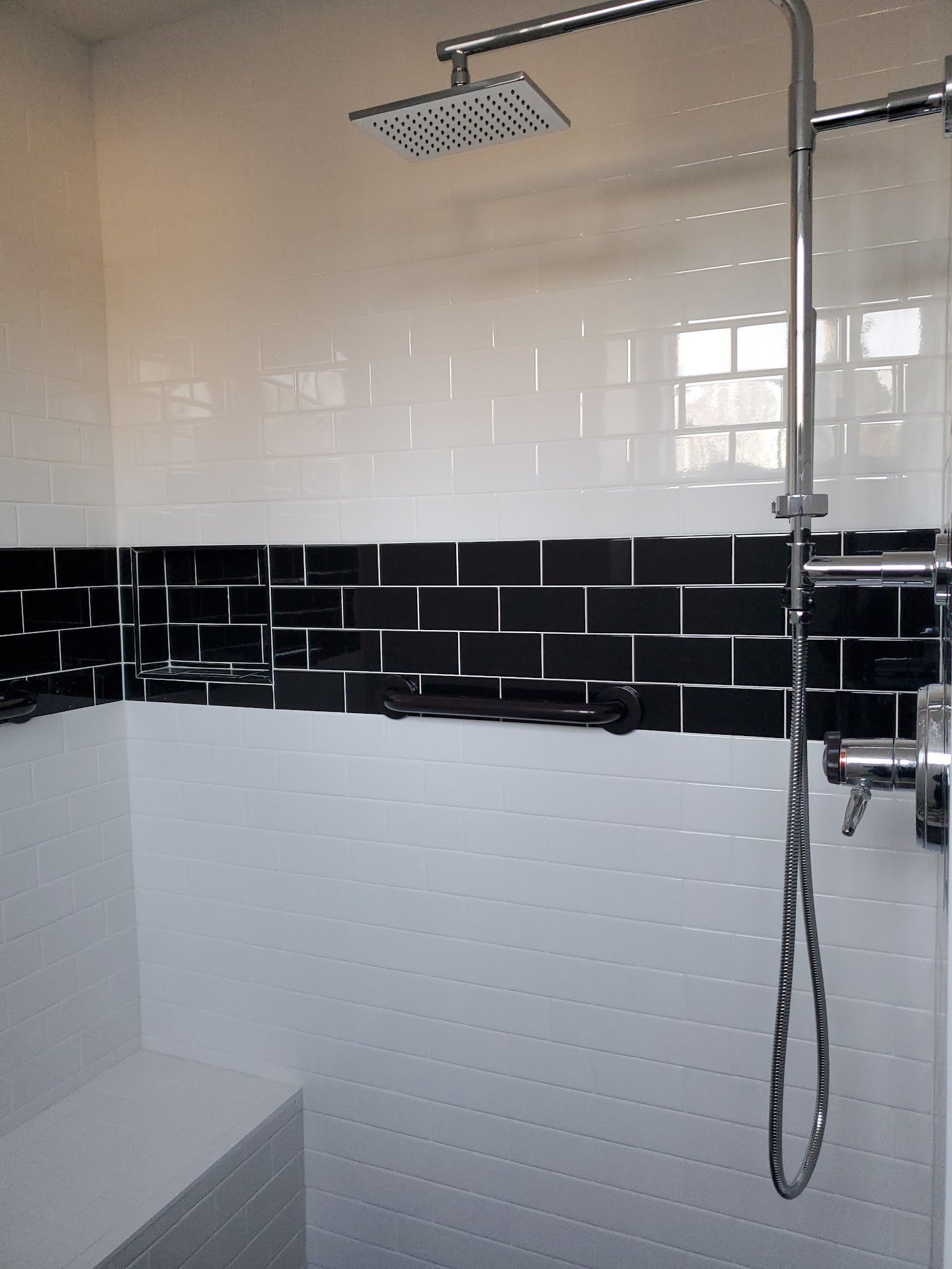 A bathroom with black and white tiles and a shower head