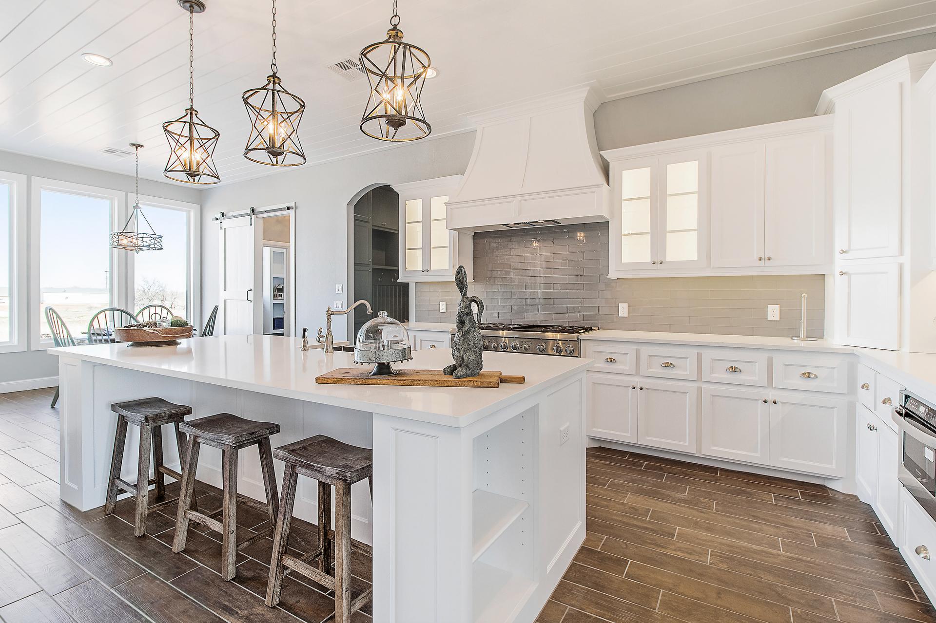 A kitchen with white cabinets and stools and a large island.