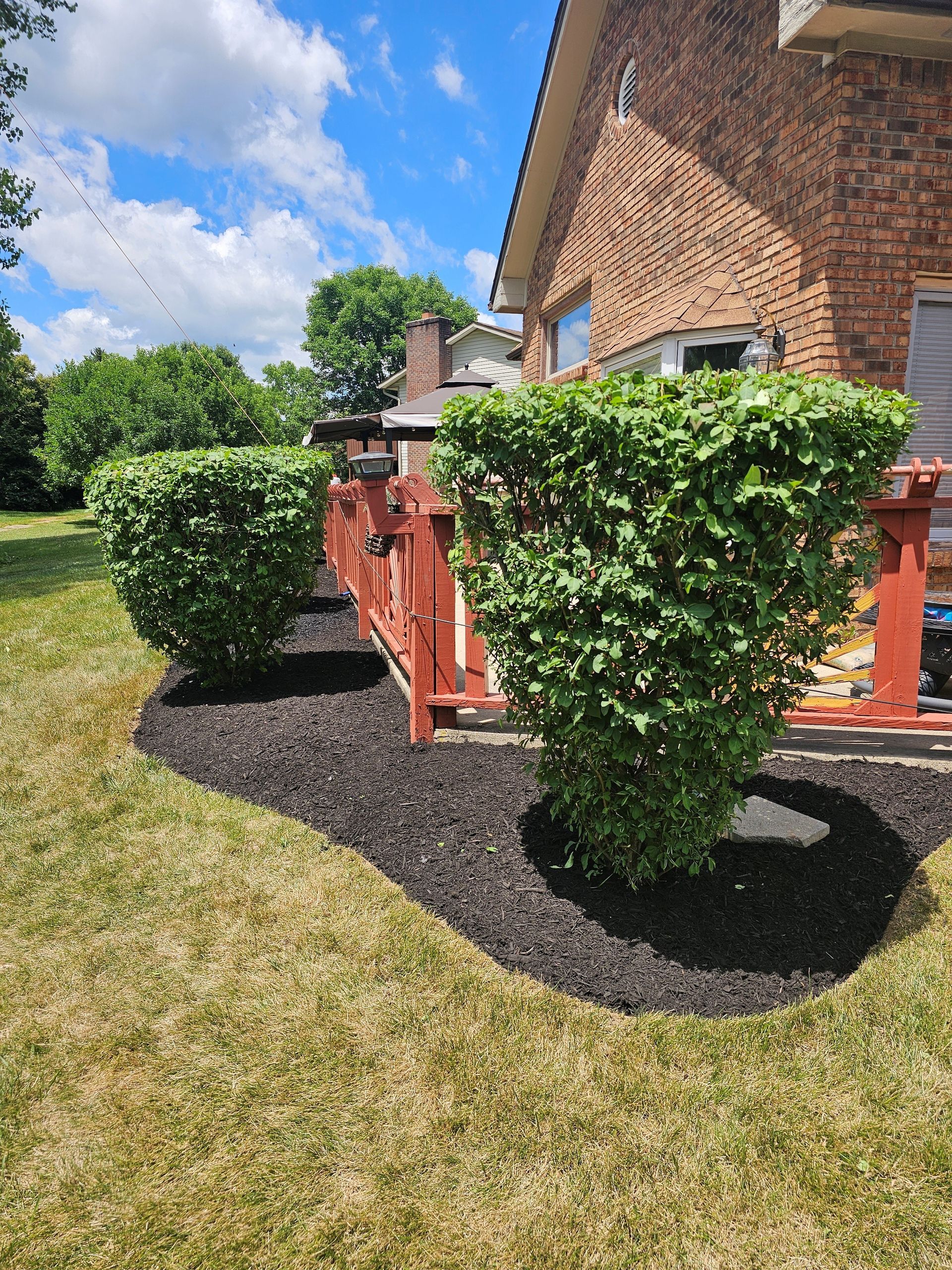 A garden with pink and white flowers in front of a house.