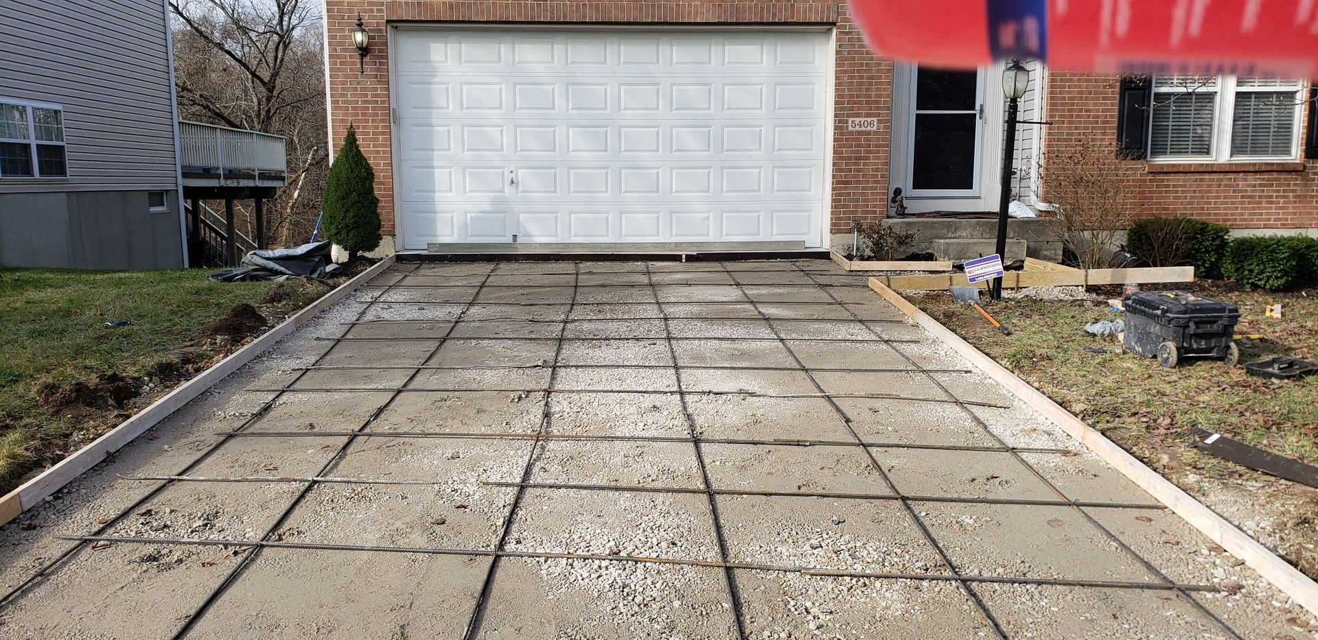A concrete driveway is being built in front of a garage door.