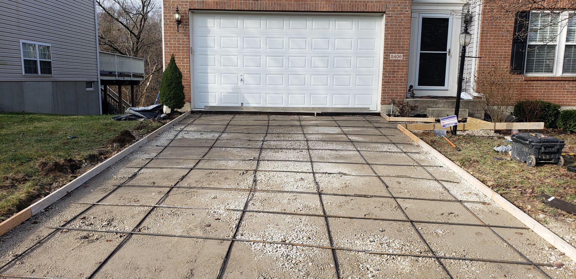 A concrete driveway is being built in front of a brick house.