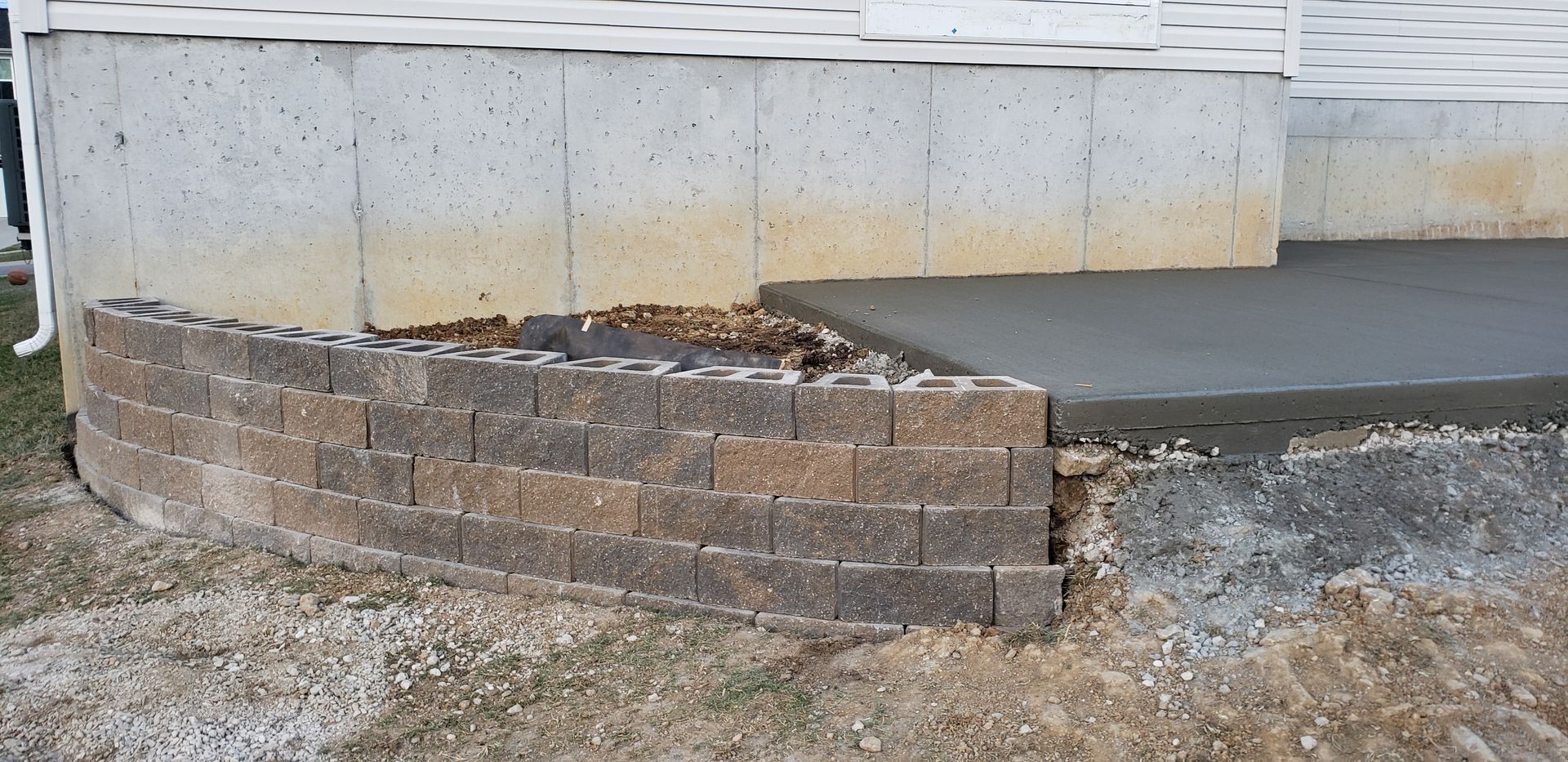A concrete walkway is being built next to a brick wall