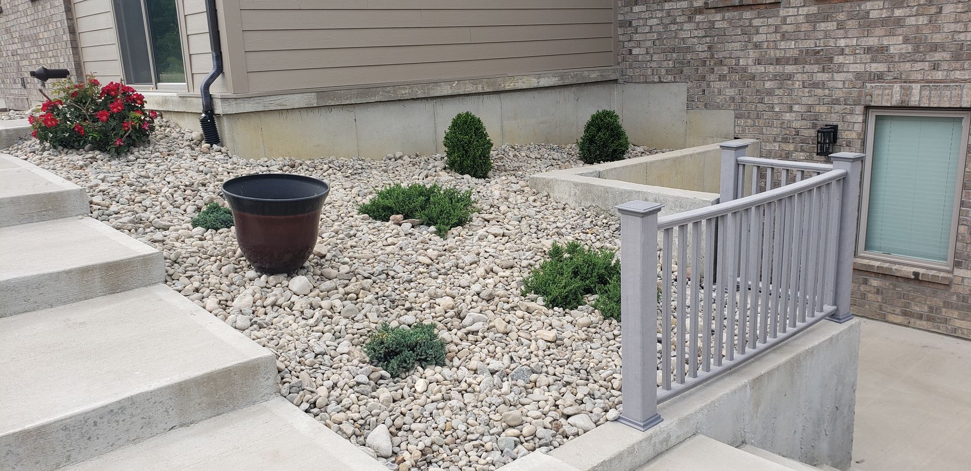 A garden with a fence and stairs in front of a house.