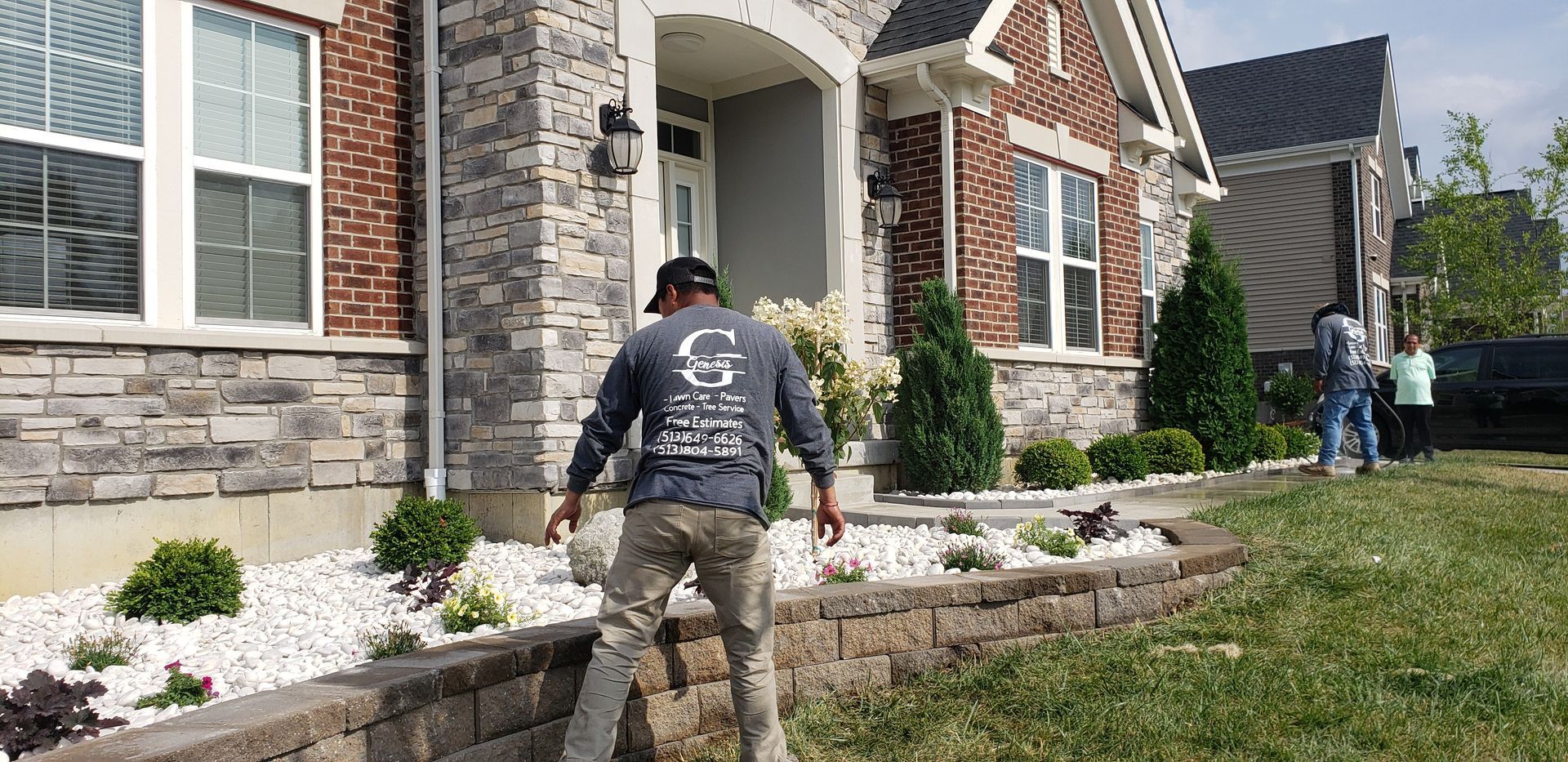 A man is standing in front of a brick house.