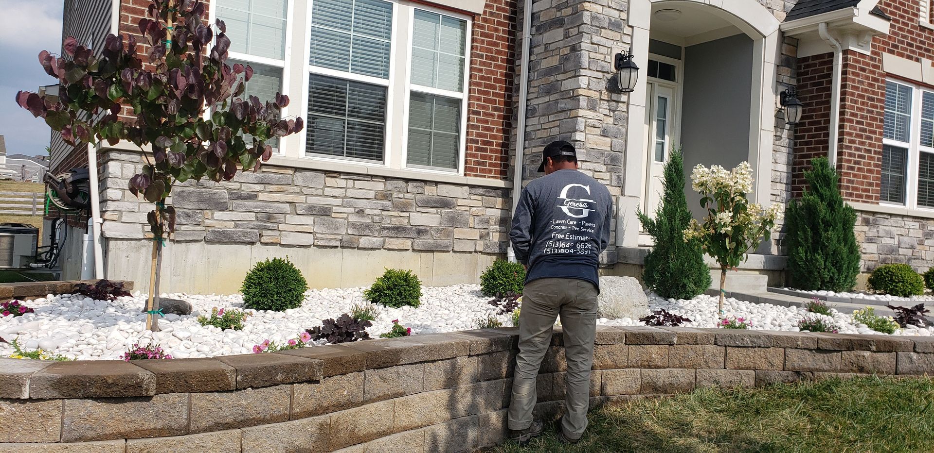 A man is standing in front of a brick house.