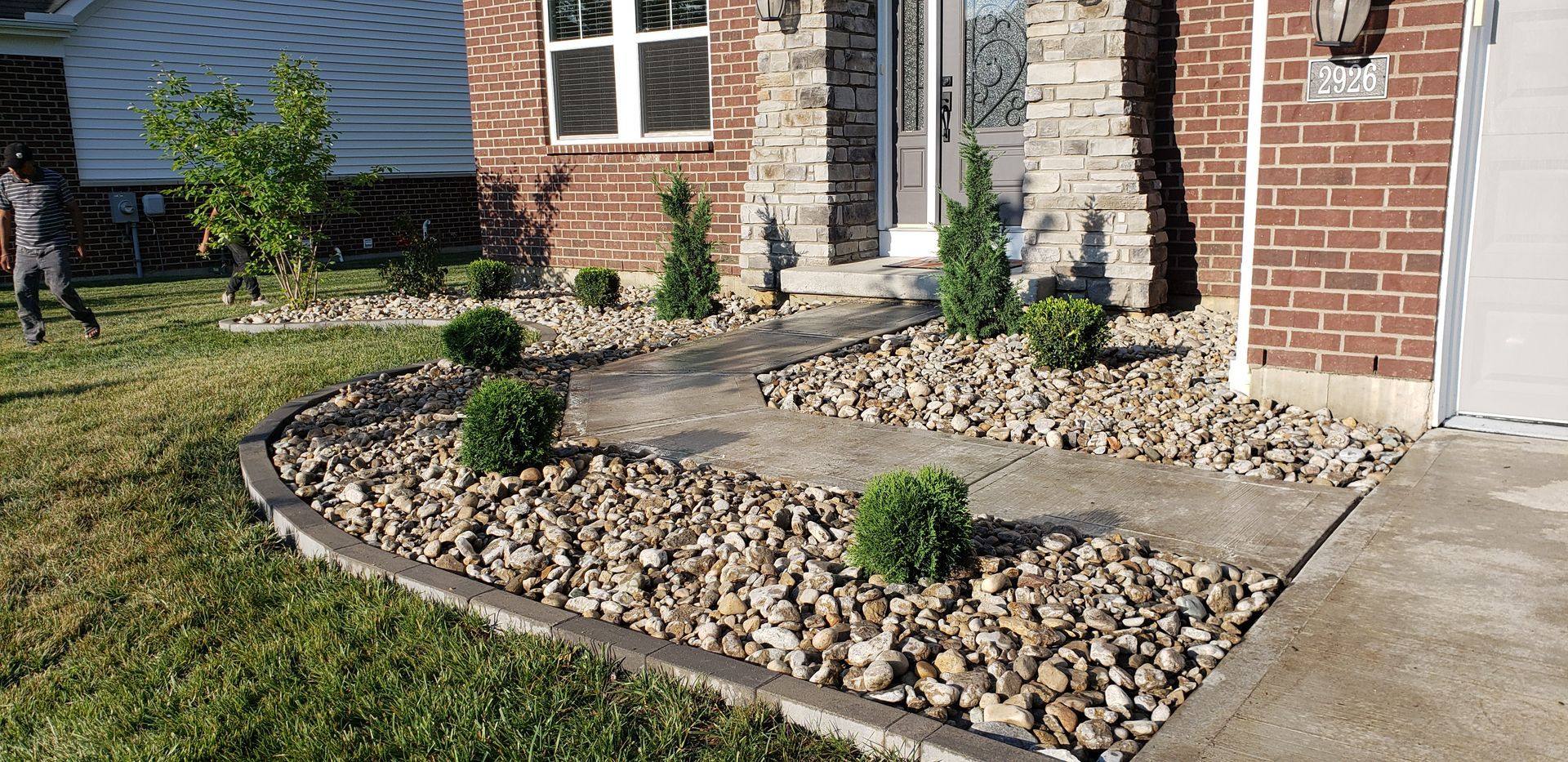 A brick house with a rock garden in front of it.