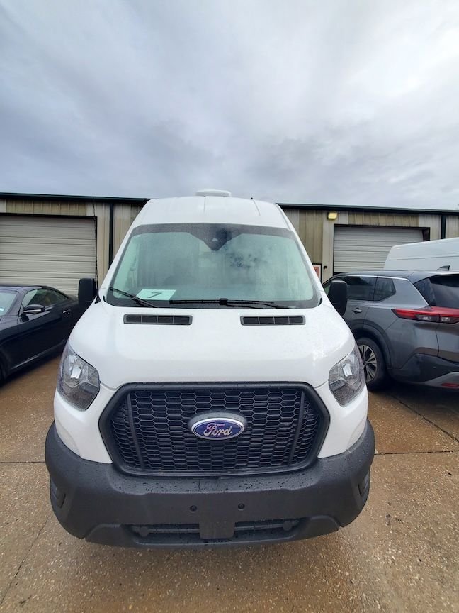 White Ford Transit van parked in front of storage units.