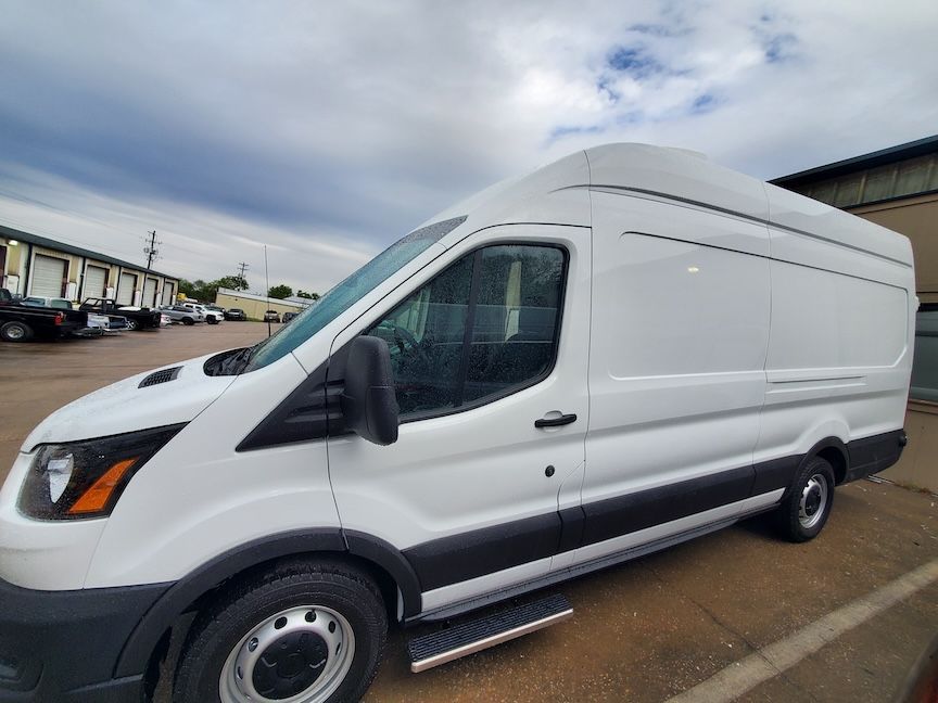 White cargo van parked outdoors under a cloudy sky.
