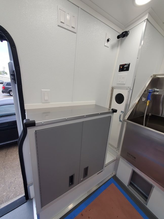 Interior of a vehicle, possibly a mobile clinic, with a cabinet, sink, and medical equipment.