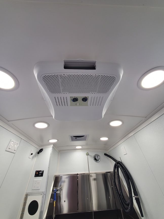 White ceiling with air conditioner, lights, and equipment in a medical vehicle.