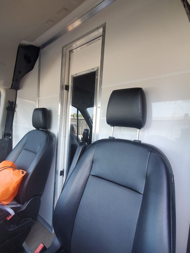 Interior of a van with two black leather seats and a door in the back.