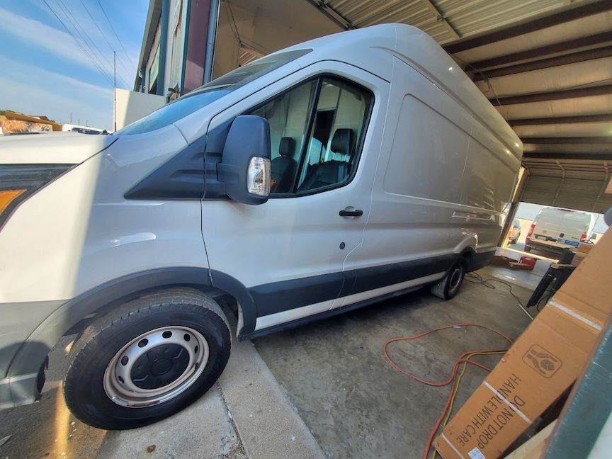 White cargo van parked partially inside a covered area.