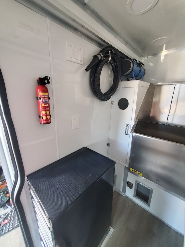 Interior of a mobile work vehicle: fire extinguisher, equipment, cabinets, and a black box.