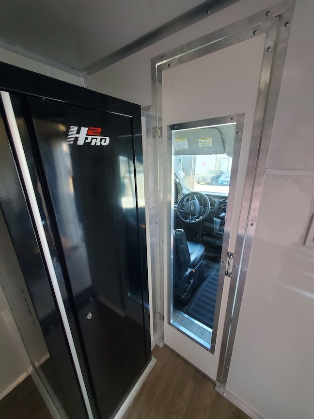 Interior view: black cabinet next to a door with a window, leading to a vehicle's interior.