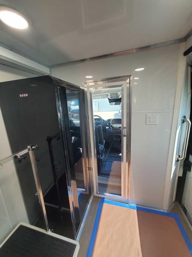 Interior view of a grooming van, showing a black cabinet, entry door, and light fixtures.