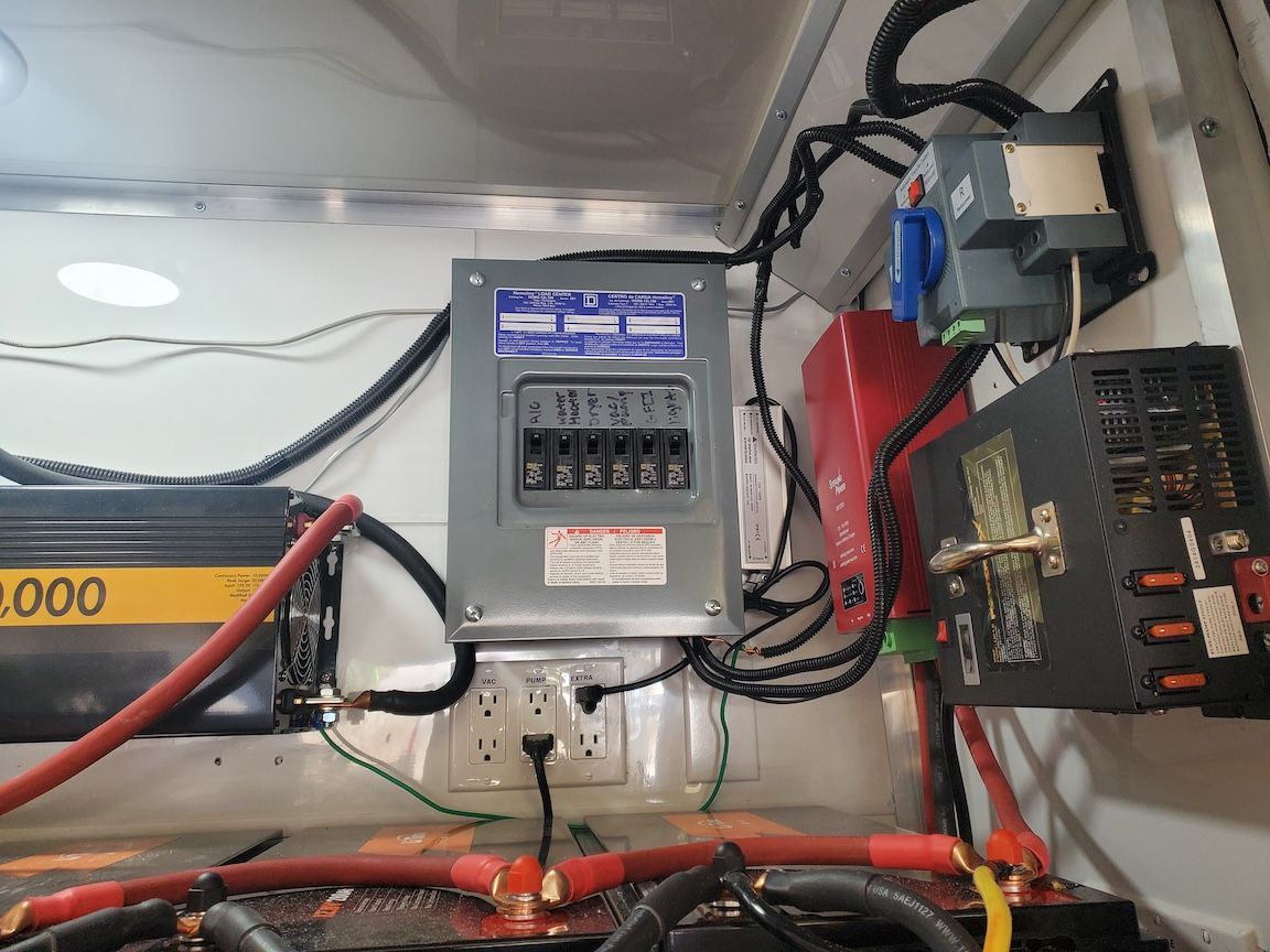 Electrical panel with breakers, outlets, inverter, and wiring inside a vehicle.