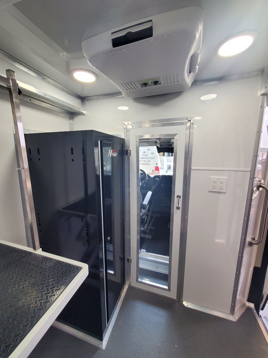 Interior of a mobile grooming trailer with equipment and a door to the driving area.