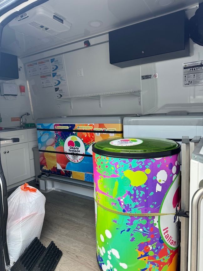 Interior of an ice cream truck with colorful freezer and trash bags.