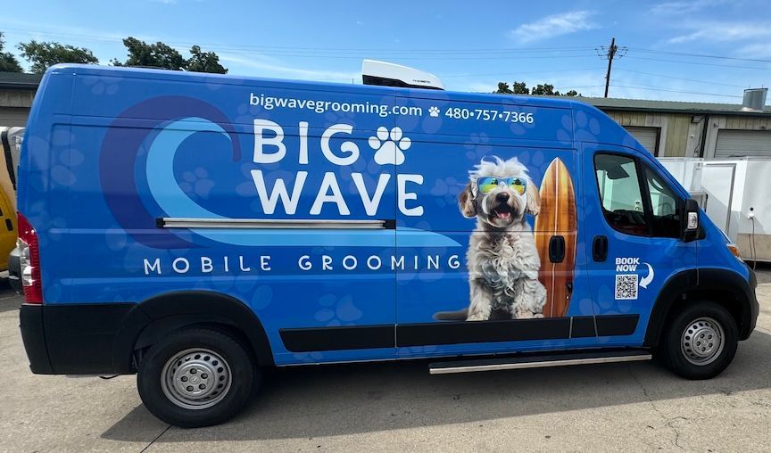 Blue Big Wave mobile grooming van with a dog graphic and surfboard.