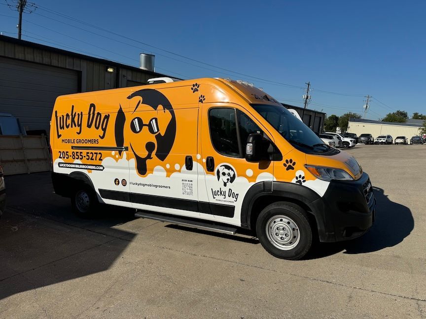 Yellow Lucky Dog mobile grooming van parked outdoors.