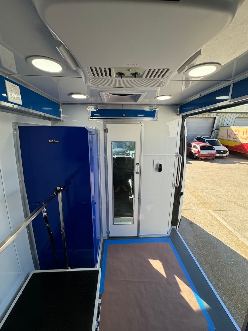 Inside of a mobile pet grooming van, with blue and white interior, equipment and tools.