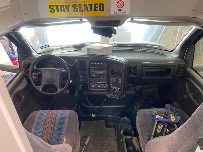The interior of a van with a sticker on the dashboard that says `` stay seated ''.