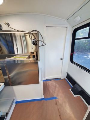 A kitchen in a bus with stainless steel appliances and a sink.