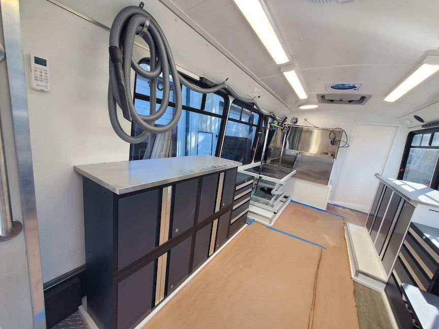 The inside of a bus with a vacuum hose hanging from the ceiling.