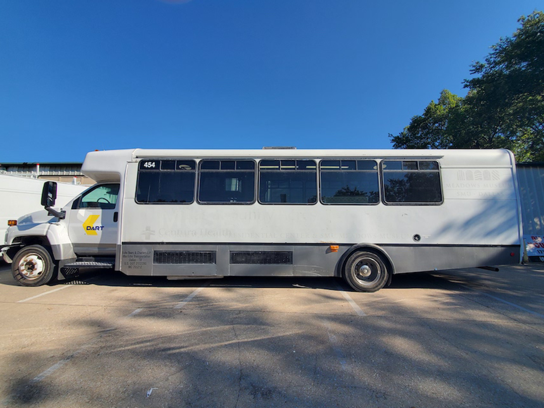 A white bus is parked in a parking lot.