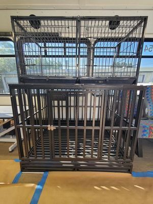 A large metal cage is sitting on top of a wooden floor in a room.