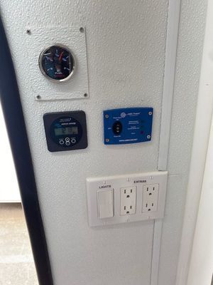 A white wall with three electrical outlets and a thermometer on it.