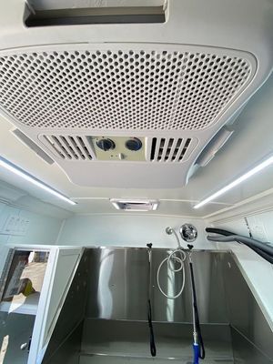 A dog grooming van with a stainless steel sink and a ceiling fan.
