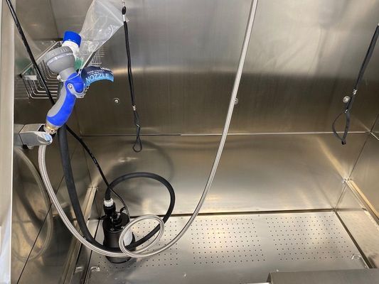 A stainless steel bathtub with a hose attached to it