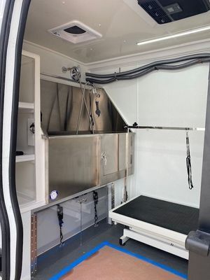 The inside of a van with a stainless steel sink and a grooming table.