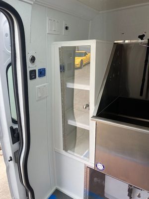 The inside of a white van with a stainless steel sink and shelves.