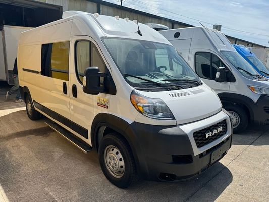 Two white vans are parked next to each other in a parking lot.