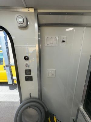 The inside of a bus with a vacuum hose hanging on the wall.