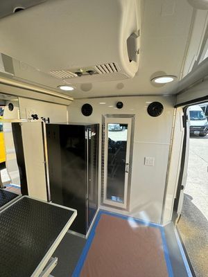 The inside of a van with a refrigerator and a table.