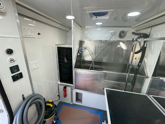 The inside of a dog grooming van with a stainless steel sink.