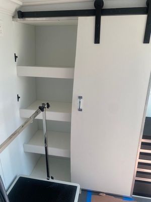 A white cabinet with shelves and a sliding barn door.
